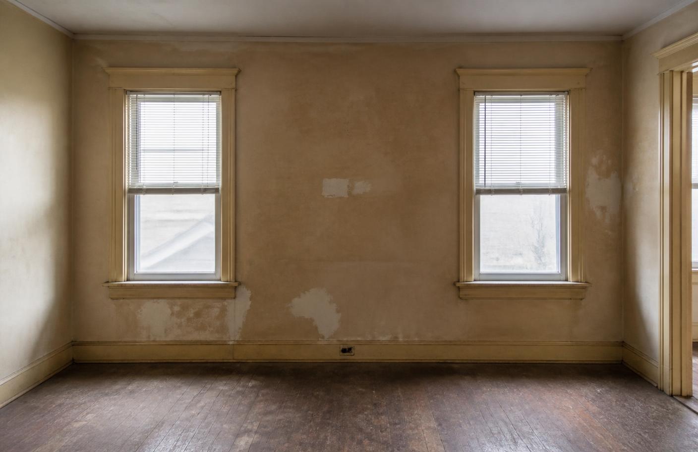 Same living room before painting with dingy scuffed walls and yellowed trim