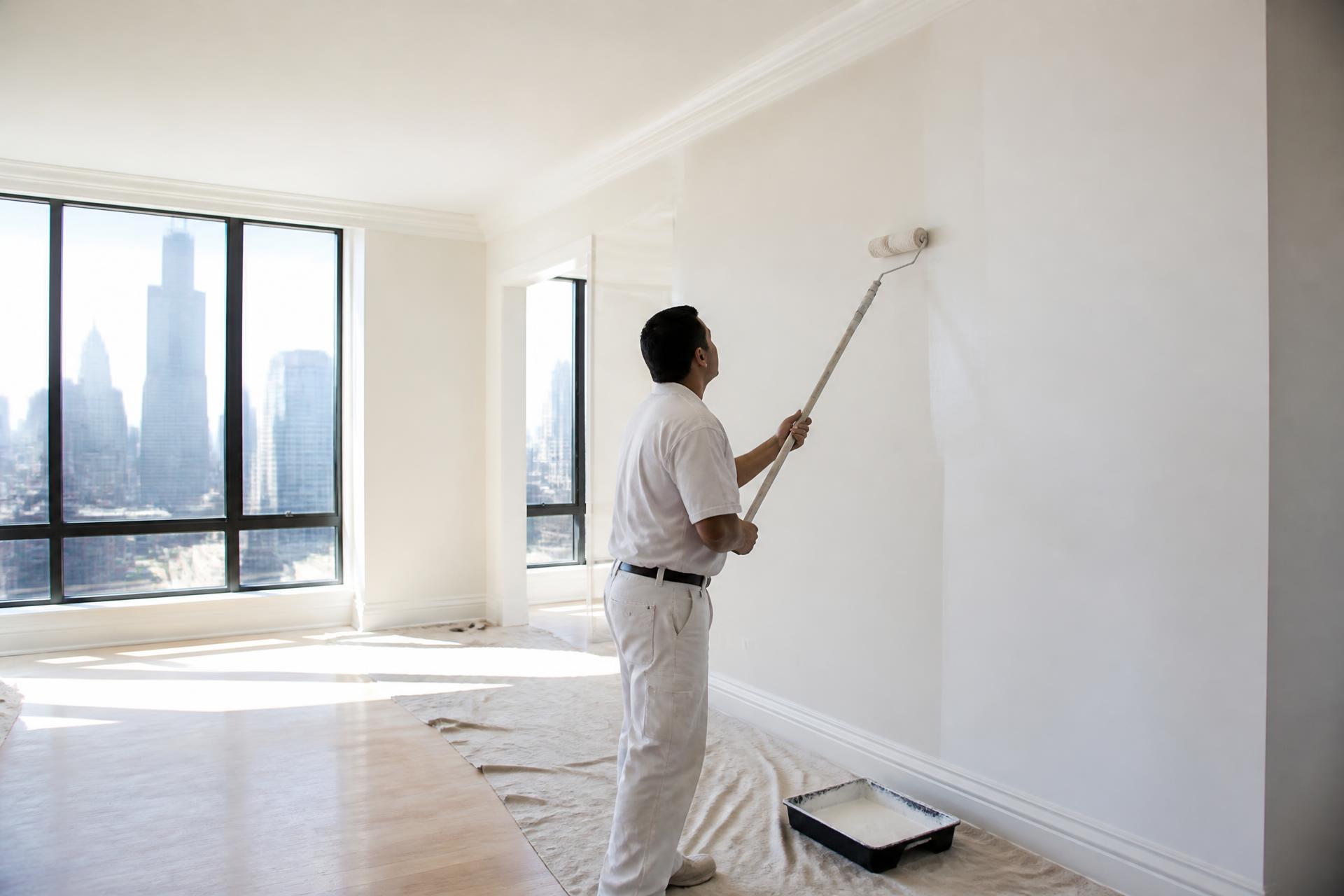 Professional painter rolling deep navy paint on an interior wall of a Chicago apartment